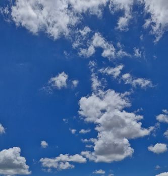 Expansive blue sky featuring fluffy cumulus clouds on a clear day.