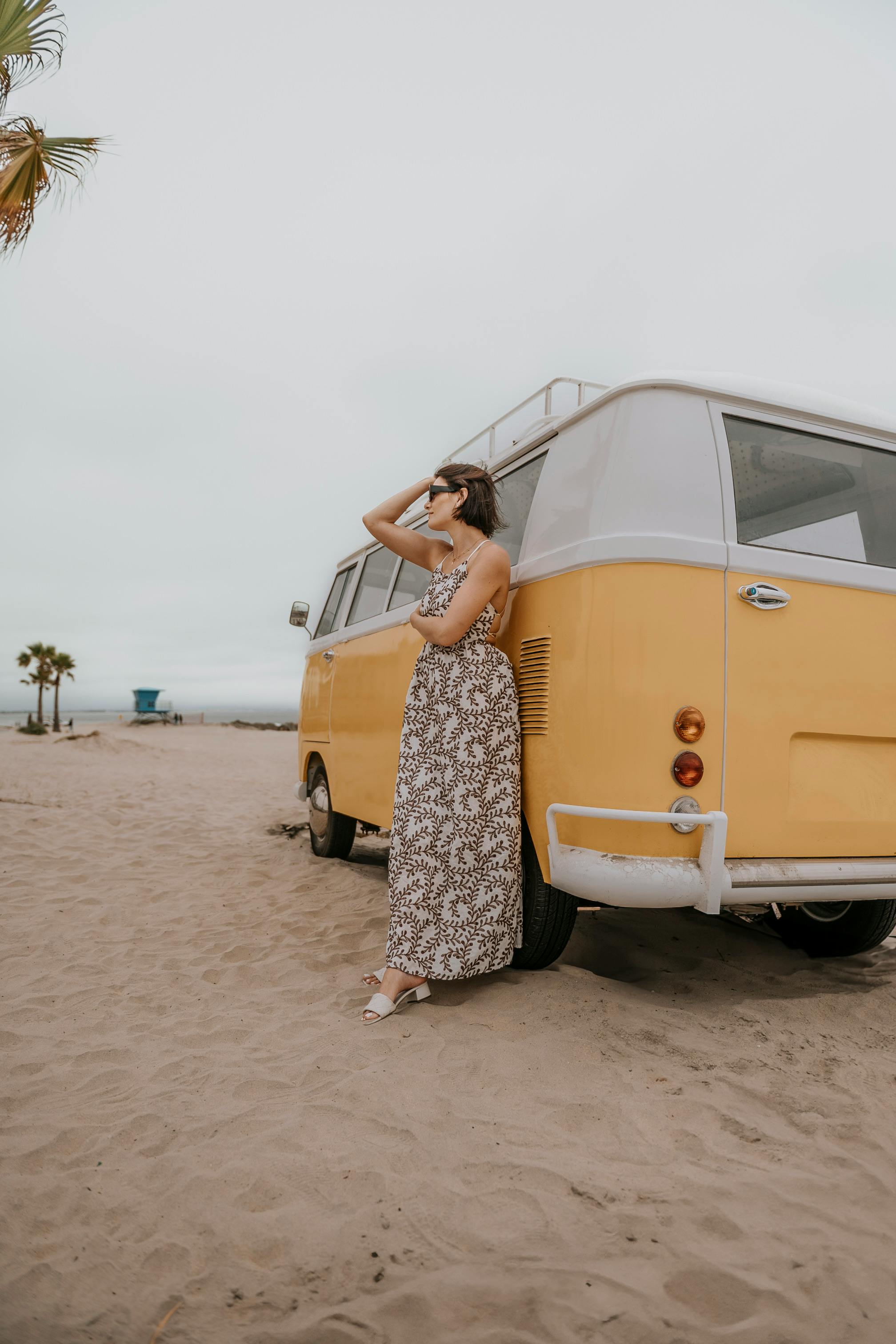 woman posing with retro yellow camper van on beach