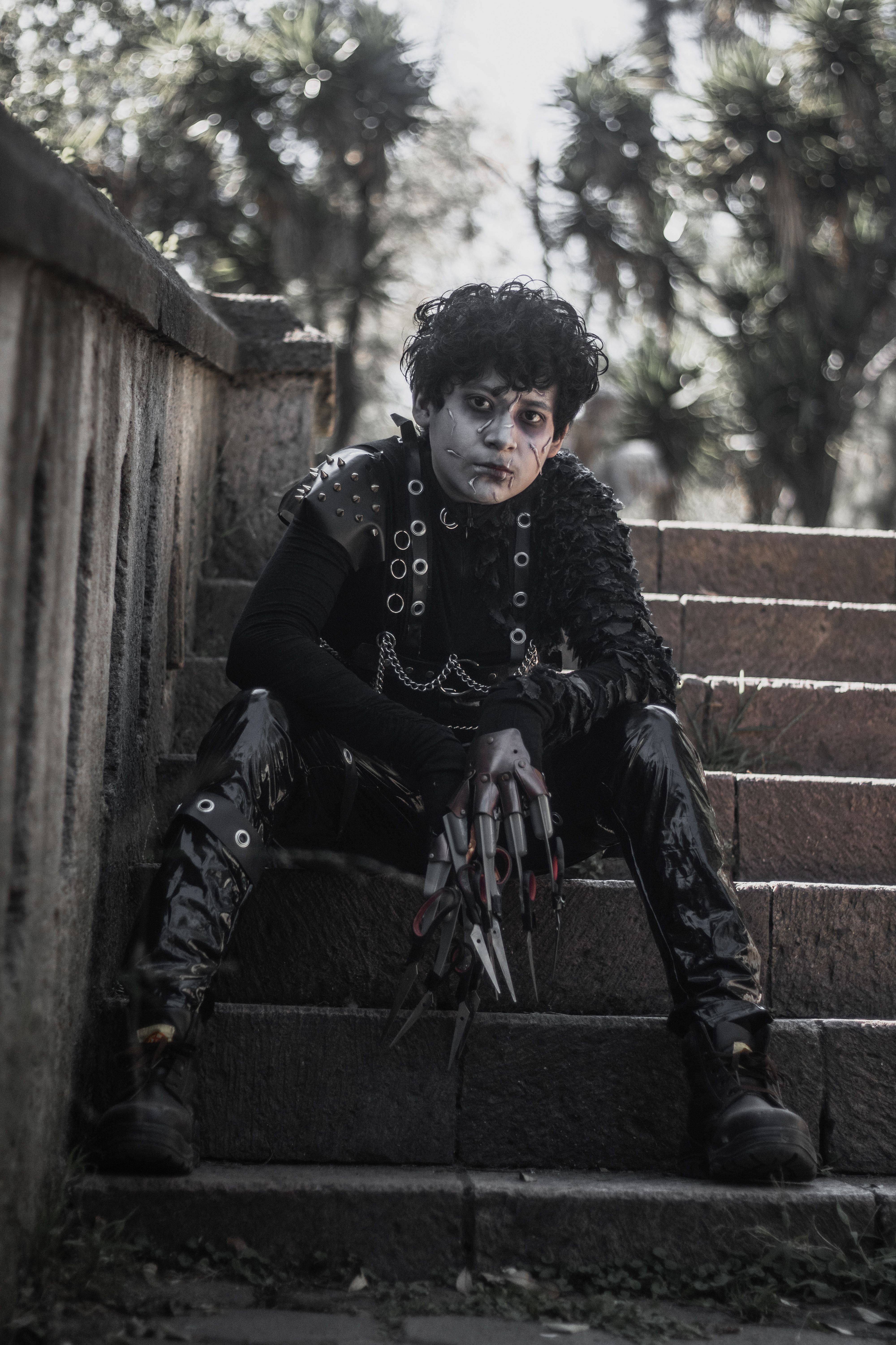 A person in detailed cosplay sits on outdoor stone steps, creating a moody ambiance.