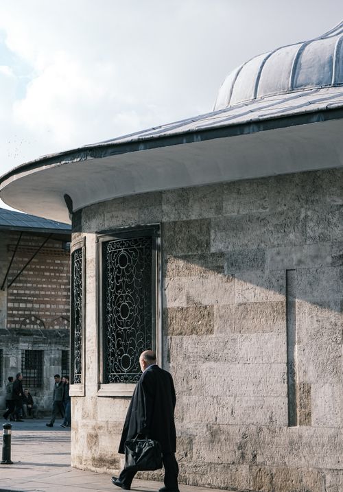 Free A man walks past a historic stone building in Istanbul, showcasing architectural details. Stock Photo