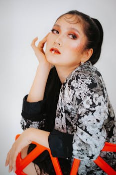 A fashionable woman with dramatic makeup and floral outfit poses for a portrait.