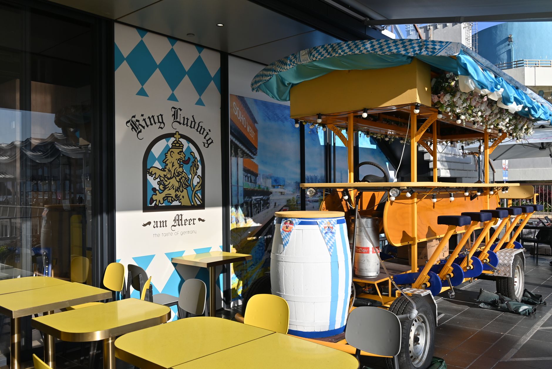 Outdoor dining area with Bavarian decor and traditional beer barrel bike setup.