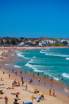 Crowded Bondi Beach filled with people enjoying a sunny day by the ocean.