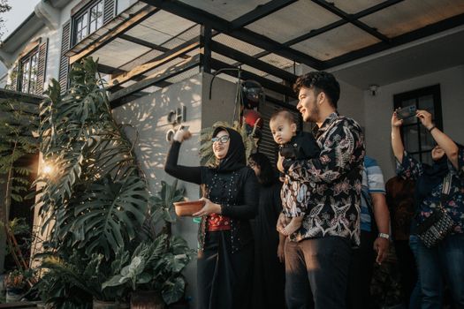 A joyful family gathering in a Surabaya backyard with lively expressions and floral decor.