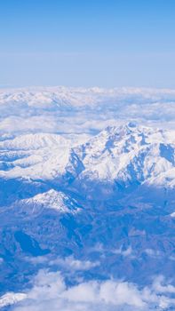 Stunning aerial view of a snow-capped mountain range under a clear blue sky.