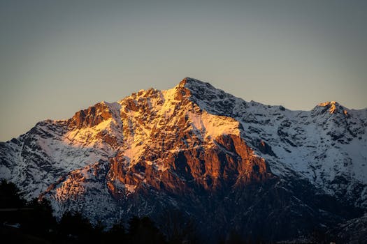 Golden sunrise illuminating a majestic snow-capped mountain peak.