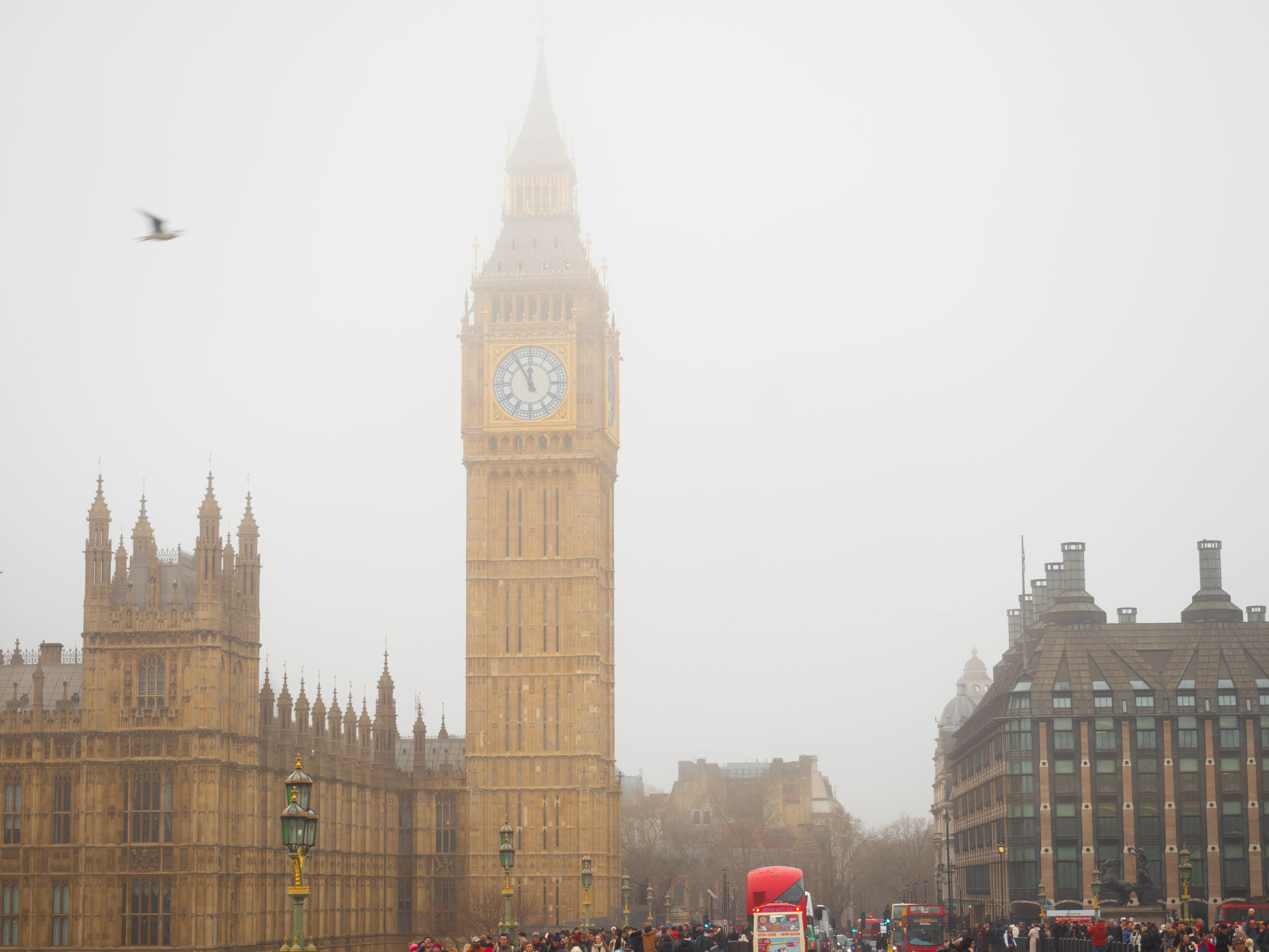 Iconic Big Ben tower enveloped in fog with bustling London street scene.