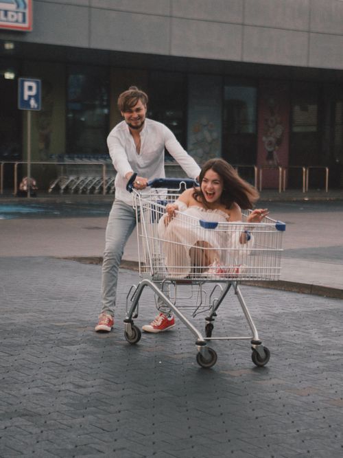 Free A carefree couple enjoying a fun ride in a shopping cart in a parking lot. Stock Photo