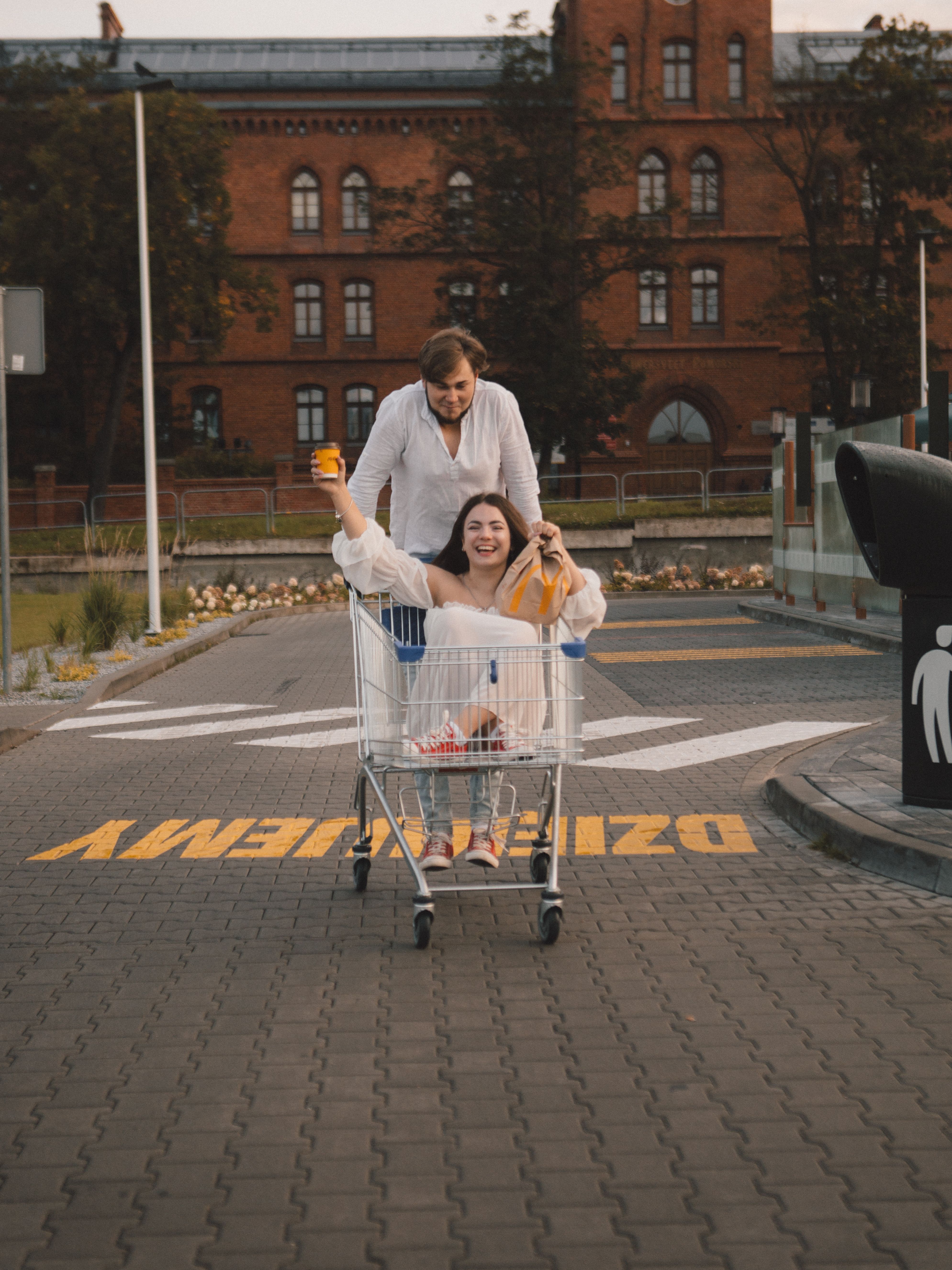 Joyful Ride in Shopping Cart Outside Brick Building · Free Stock Photo
