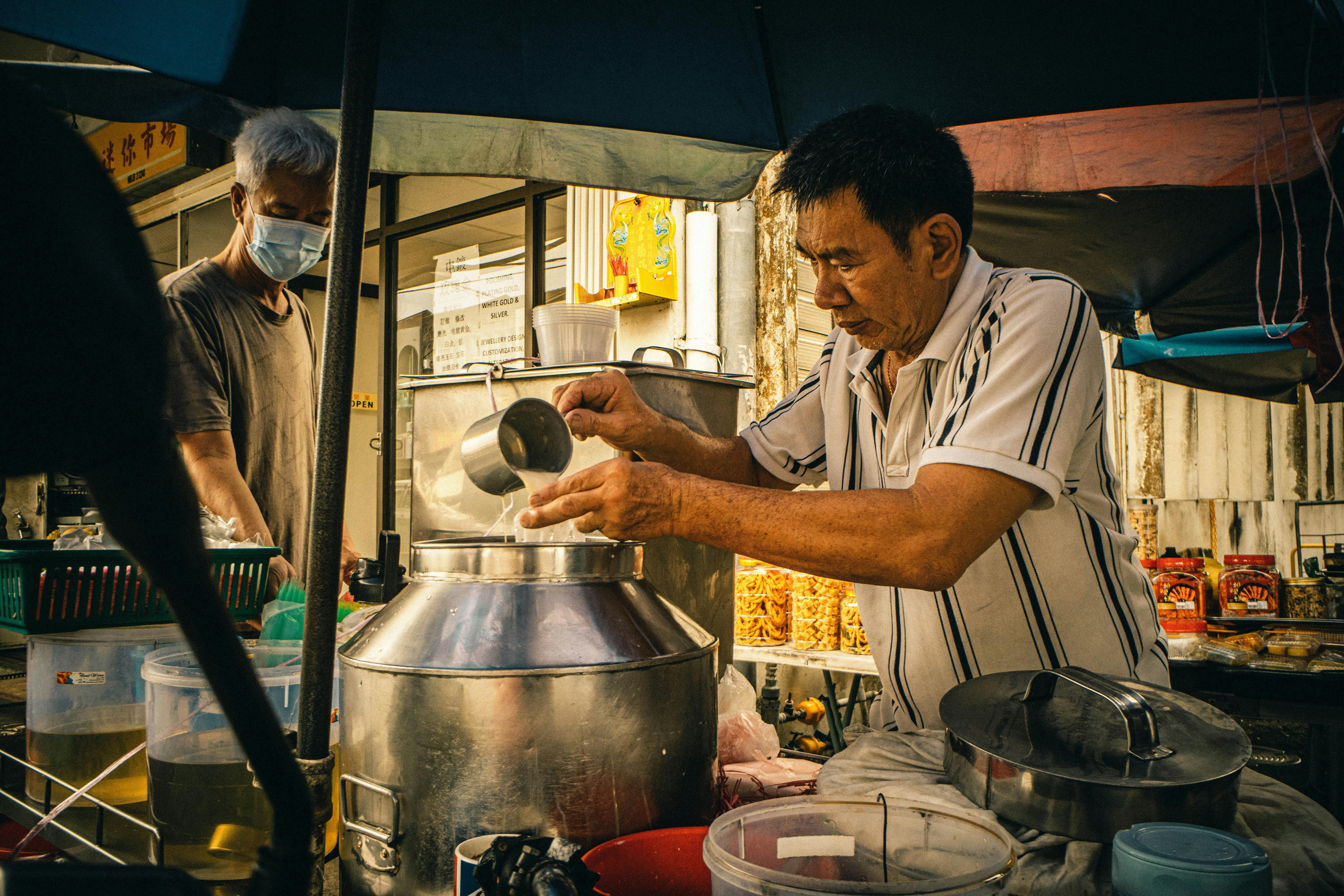 Street vendor skillfully prepares authentic Asian food in bustling market scene.