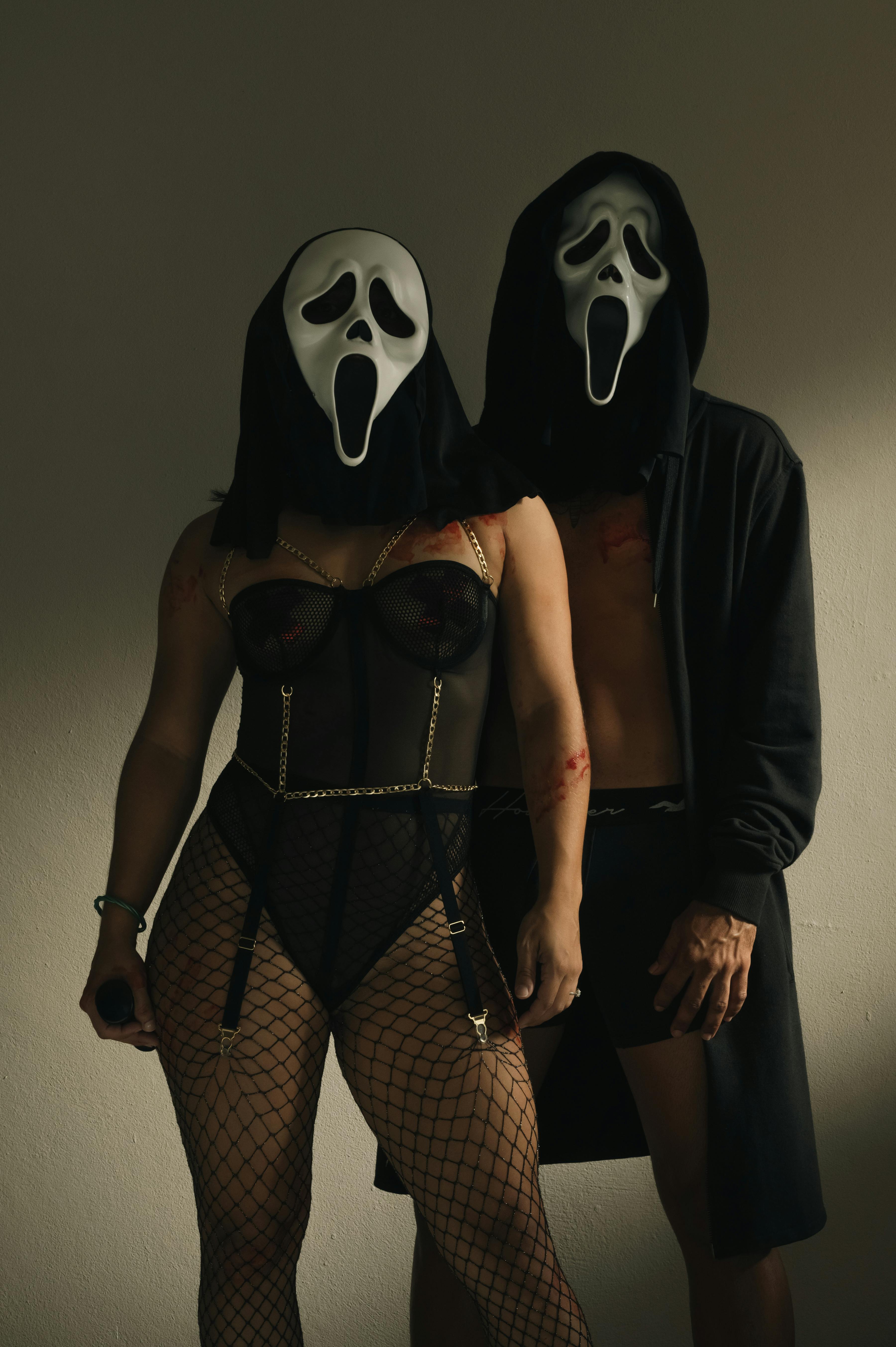 A couple dressed in Halloween costumes with scream masks posing indoors.