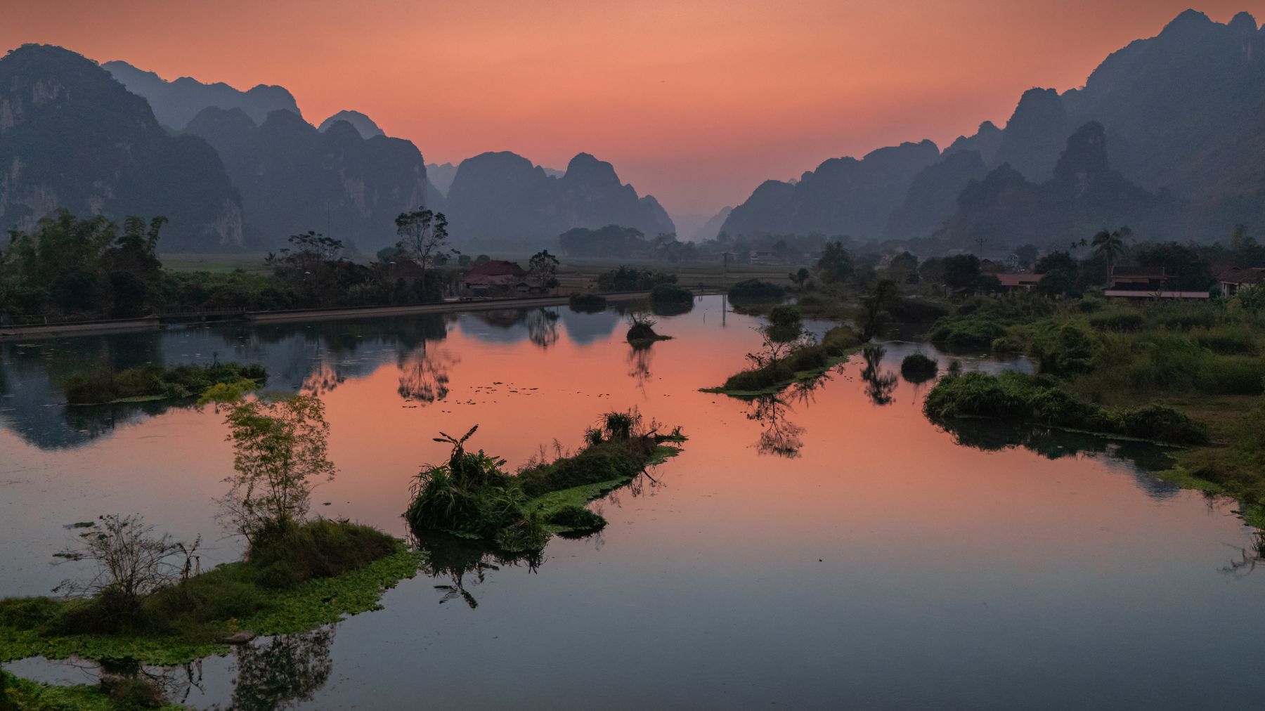 A breathtaking sunset view over the tranquil lake surrounded by mountains in Lạng Sơn, Vietnam.