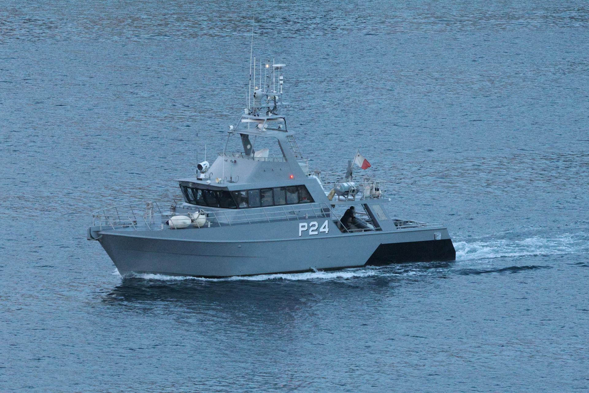 Military patrol boat cruising through ocean waters.