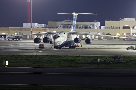 A large cargo aircraft parked on an airport runway at night, under bright lights.