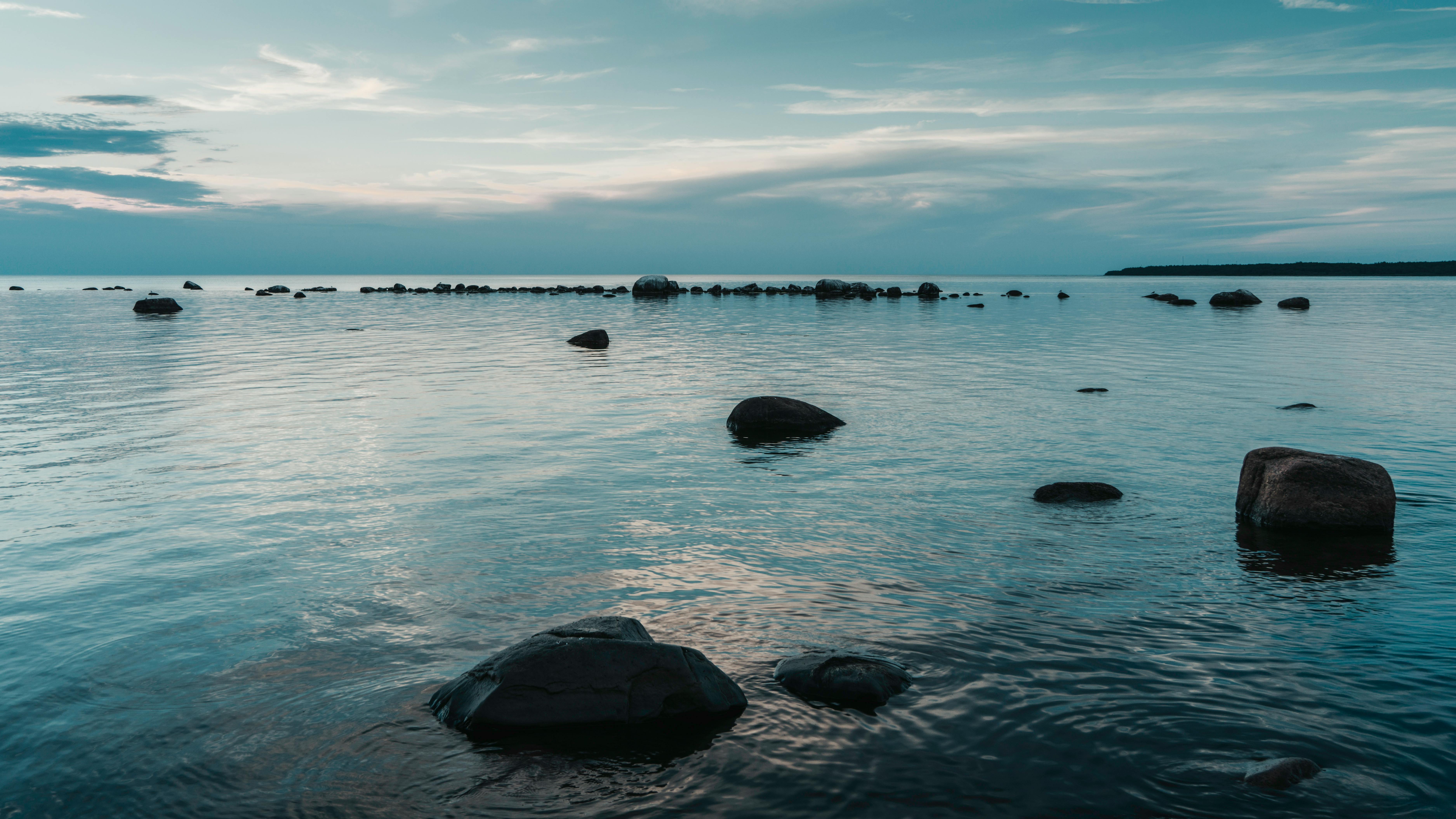 Une vue sereine de rochers dispersés sur une mer calme sous un ciel crépusculaire.