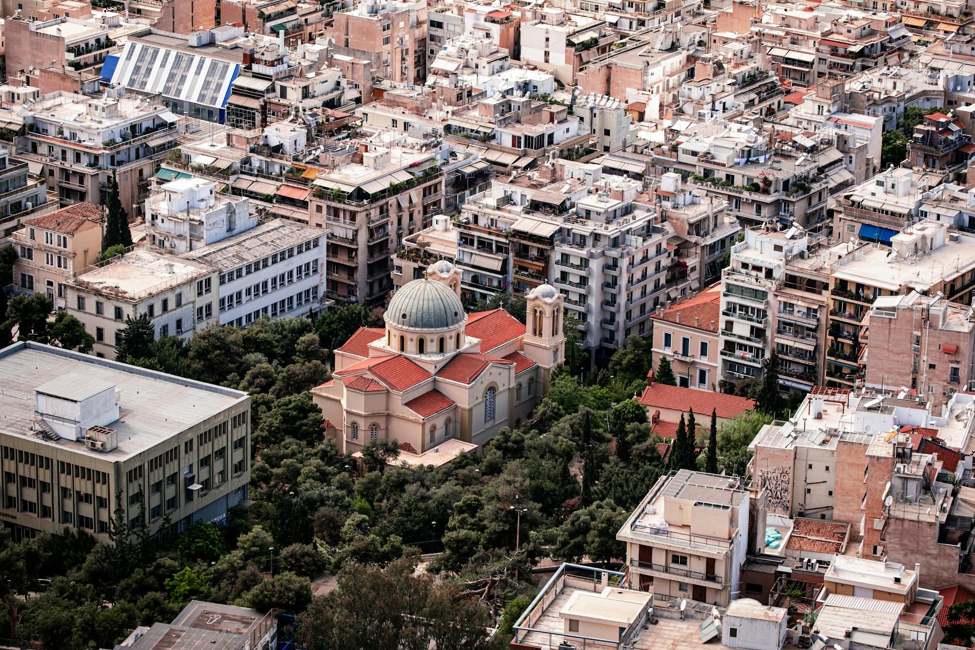 An aerial view of a cityscape featuring a church amidst high-rise buildings in an urban environment.