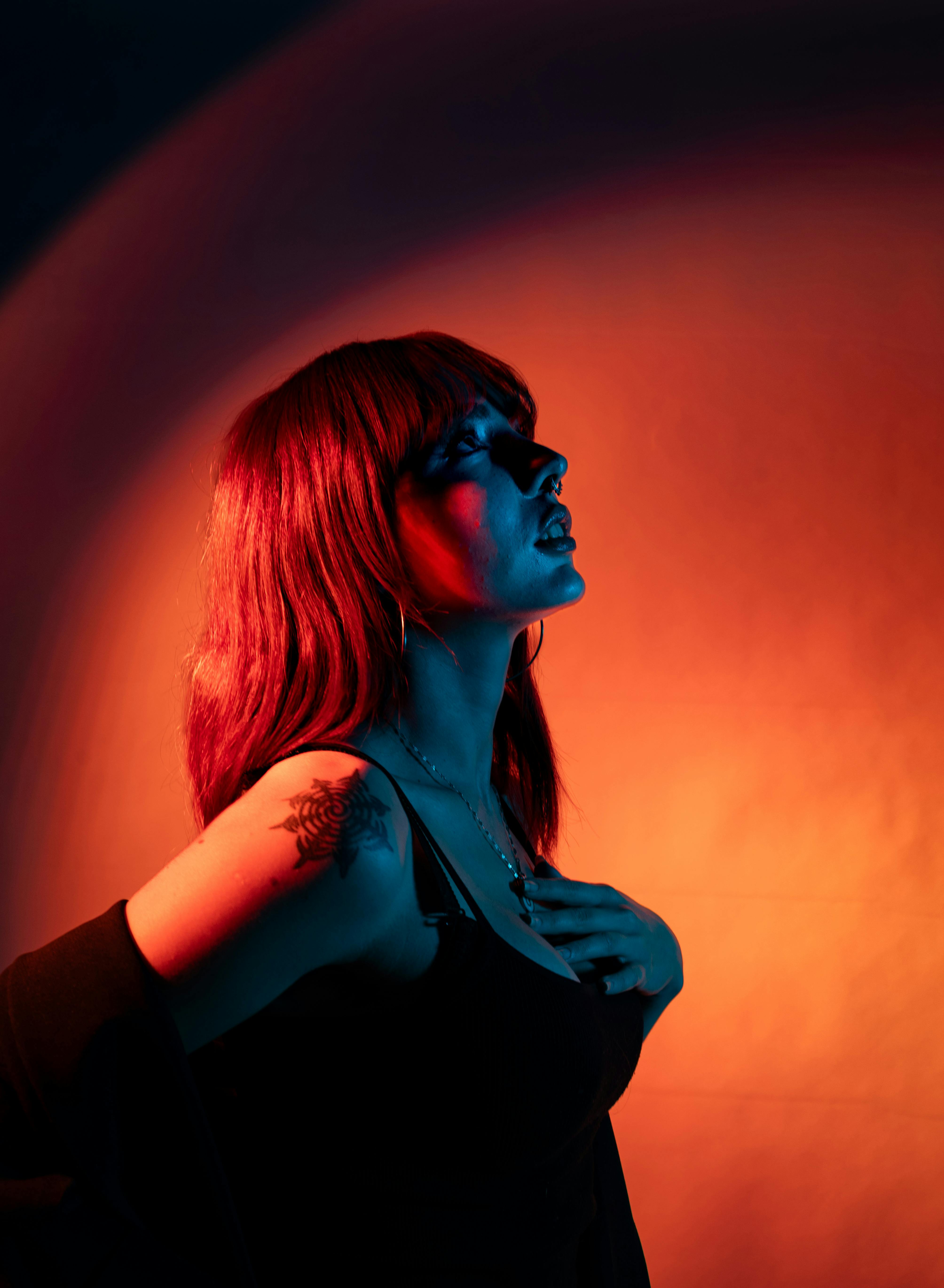 Artistic portrait featuring a woman in dramatic lighting with an orange and blue backdrop.