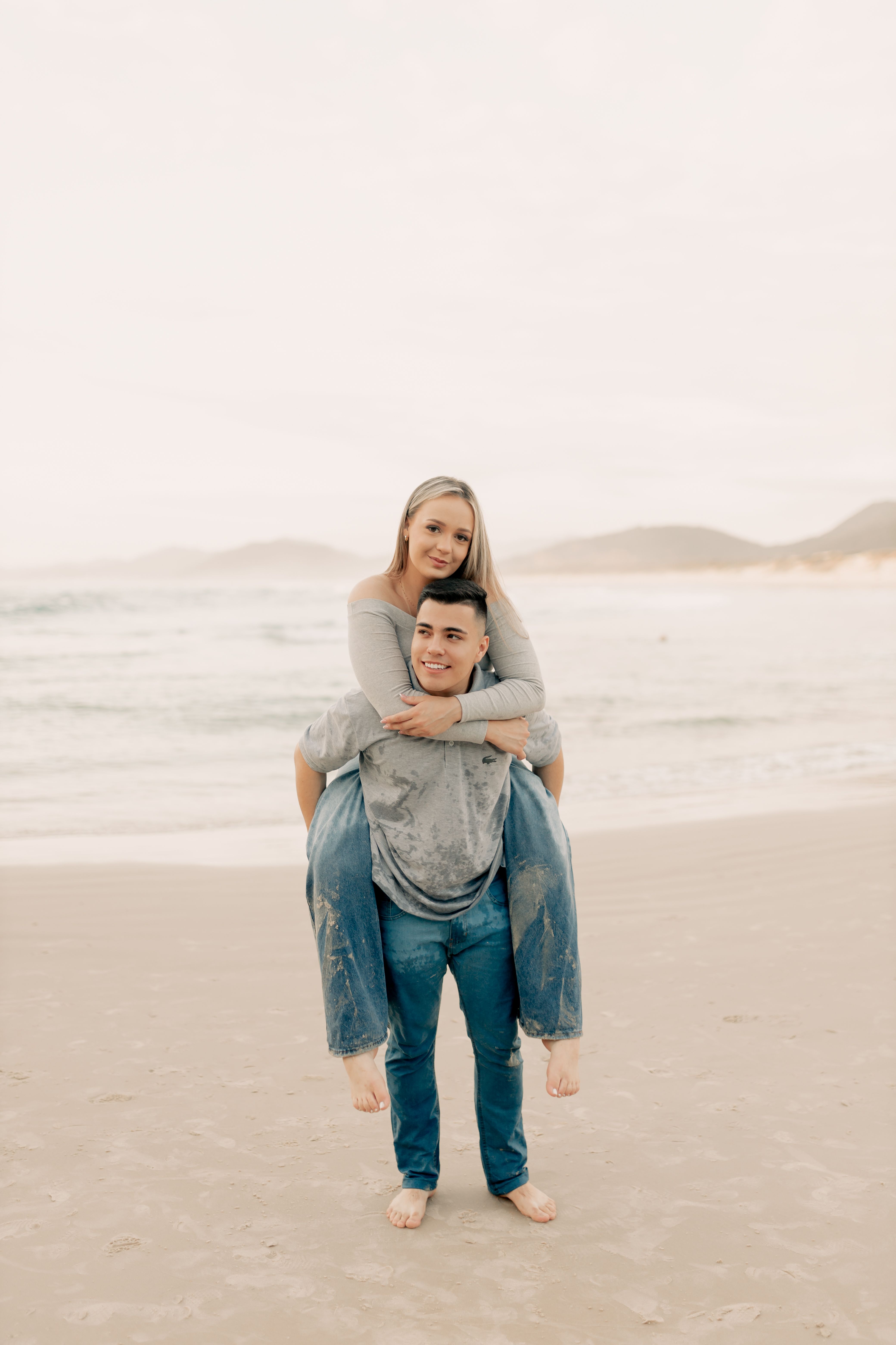 Joyful Couple Enjoying a Piggyback Ride on Beach · Free Stock Photo