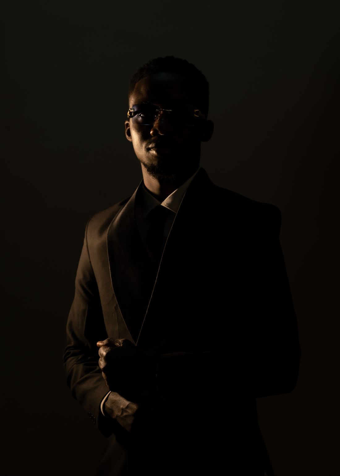 Low-key portrait of a figure in a dark tailored suit