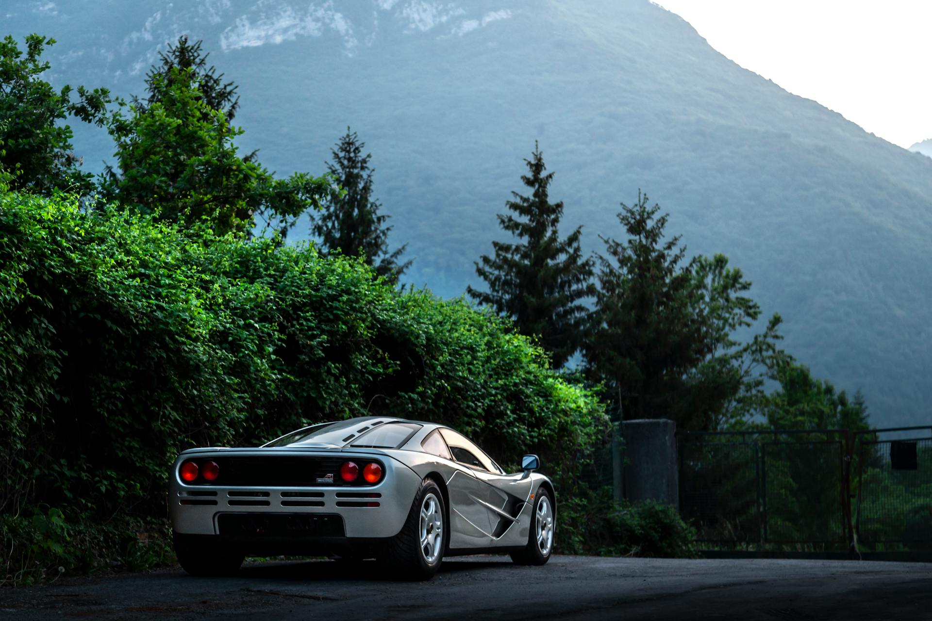 A vintage McLaren F1 sports car parked amidst the picturesque Italian Alps landscape.