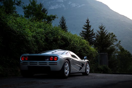Classic supercar parked in a picturesque mountain landscape at dusk, forested backdrop