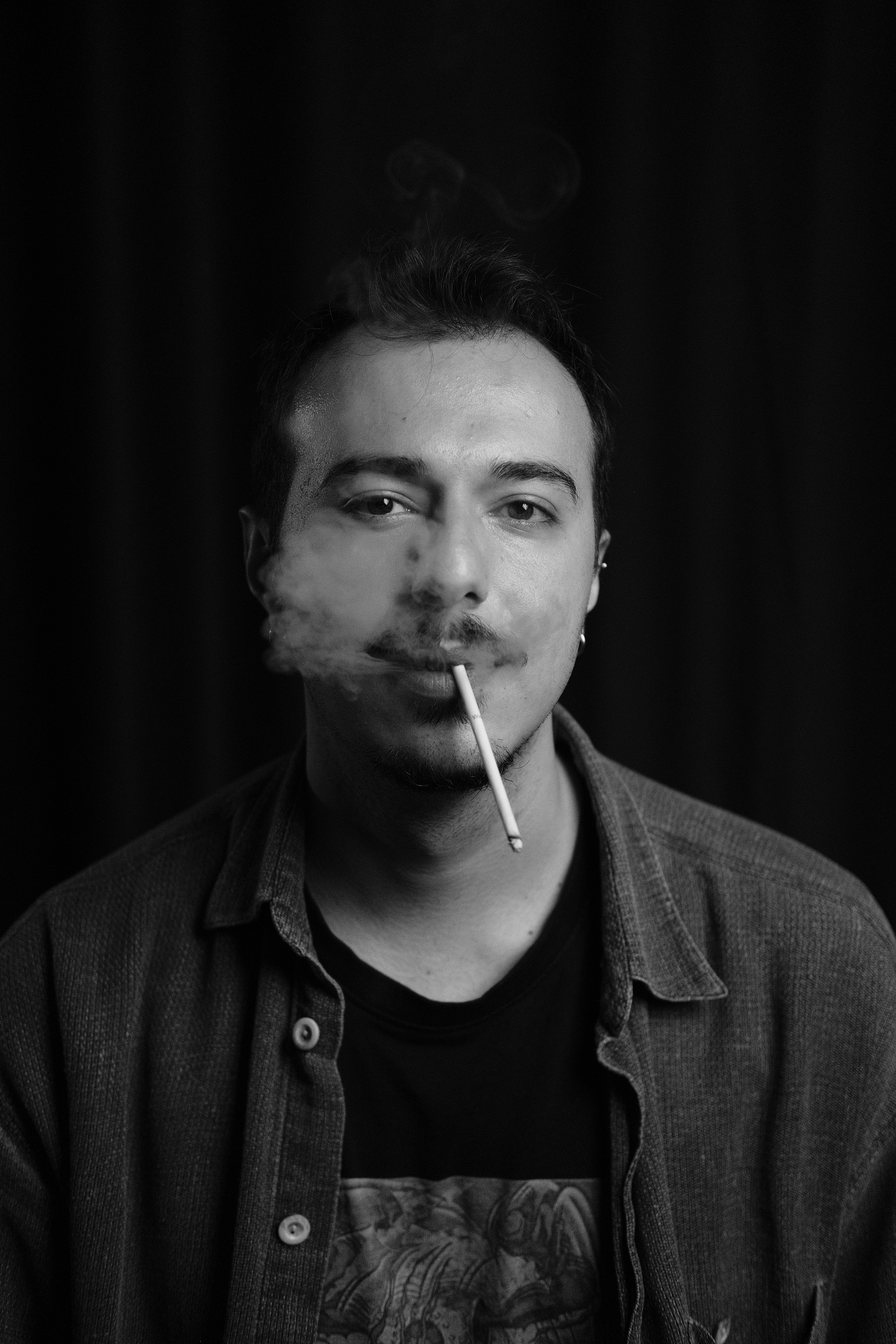 Monochrome portrait of a stylish man smoking, showcasing a modern fashion look.