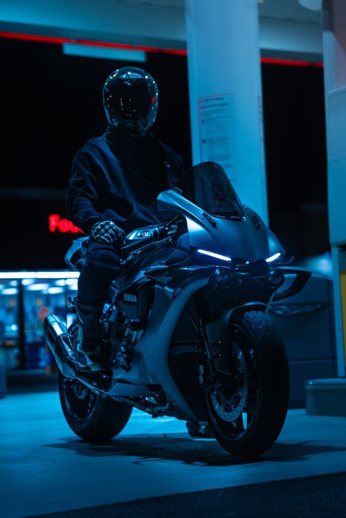 Free A motorcyclist on a sport bike at a gas station at night, creating a mysterious and adventurous mood. Stock Photo