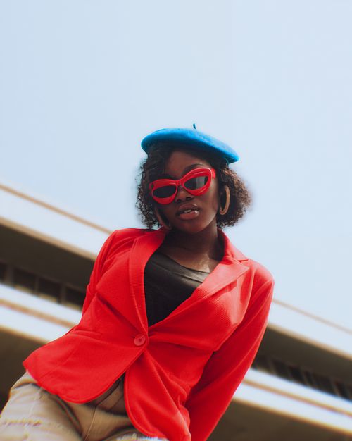 Free Portrait of a fashionable woman in vibrant clothing with red glasses and blue beret. Stock Photo