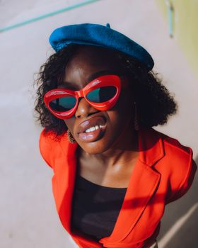 Vibrant portrait of a fashionable woman in red and blue attire, wearing sunglasses.