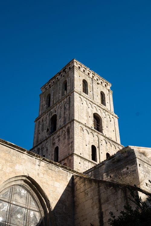 Free A striking view of a historic stone tower in Arles, France, under a clear blue sky. Perfect for travel themes. Stock Photo
