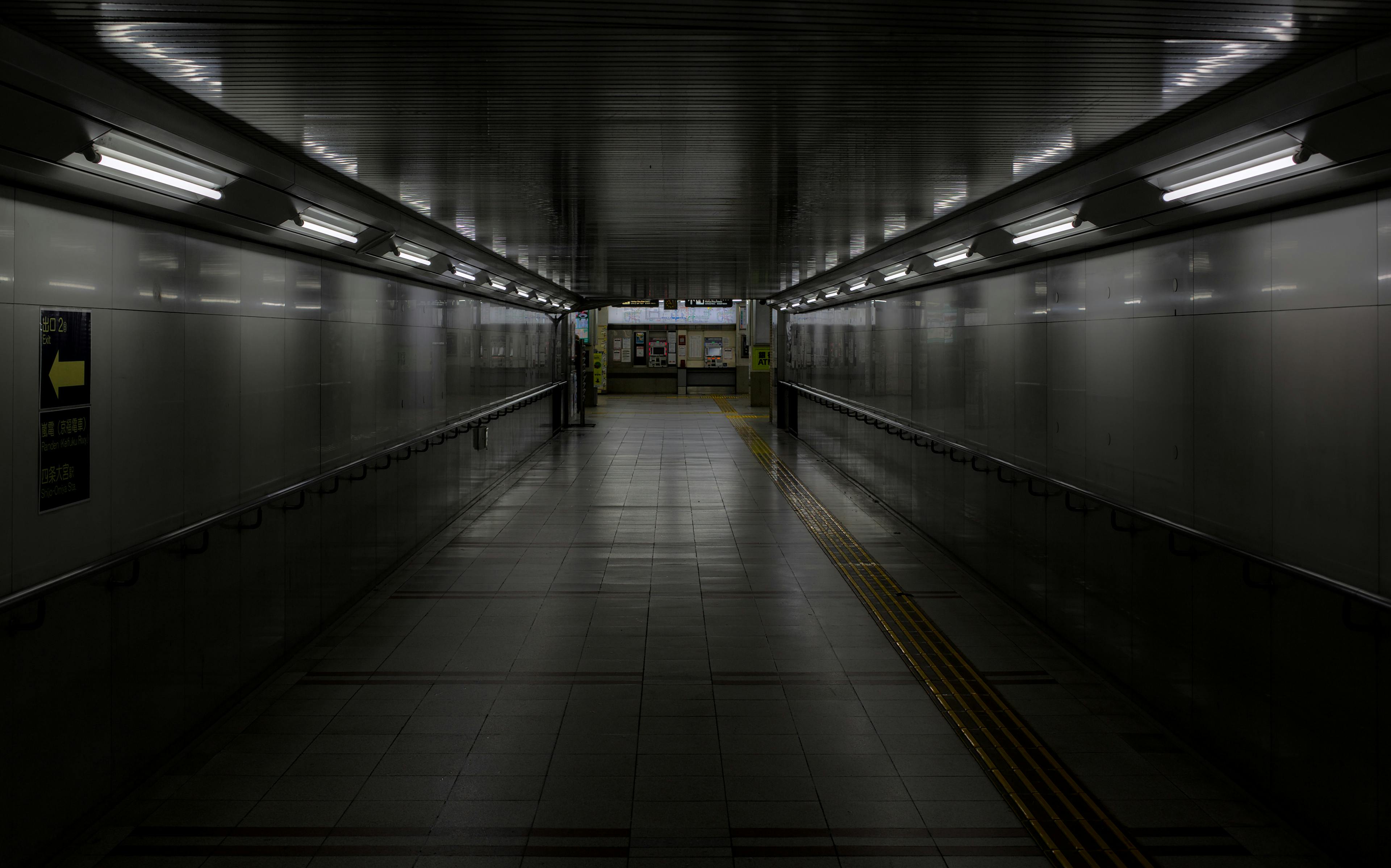 Dark and symmetrical underground tunnel in Kyoto with overhead lights and pathway guides.