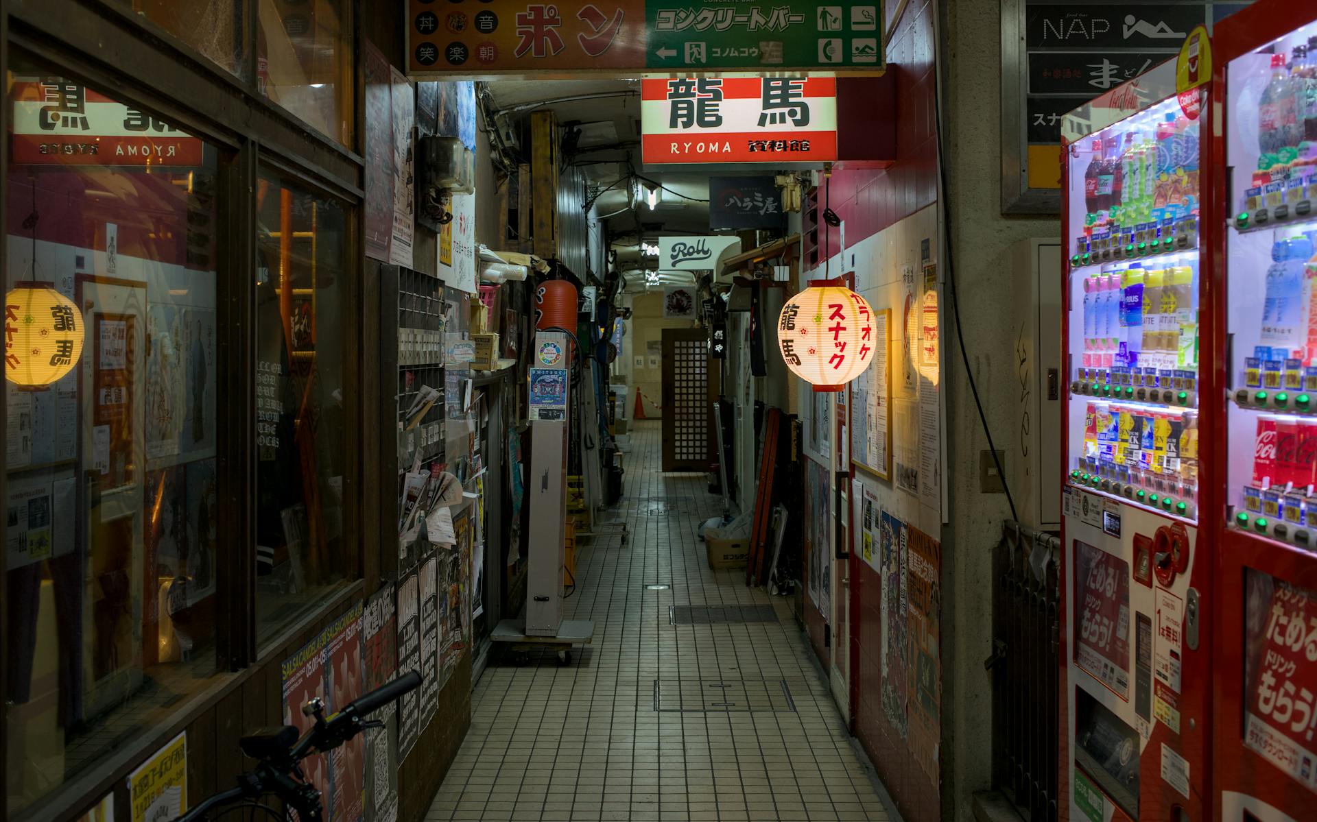 Explore a narrow alley in Kyoto at night, adorned with lanterns and vending machines. Perfect blend of tradition and modernity.