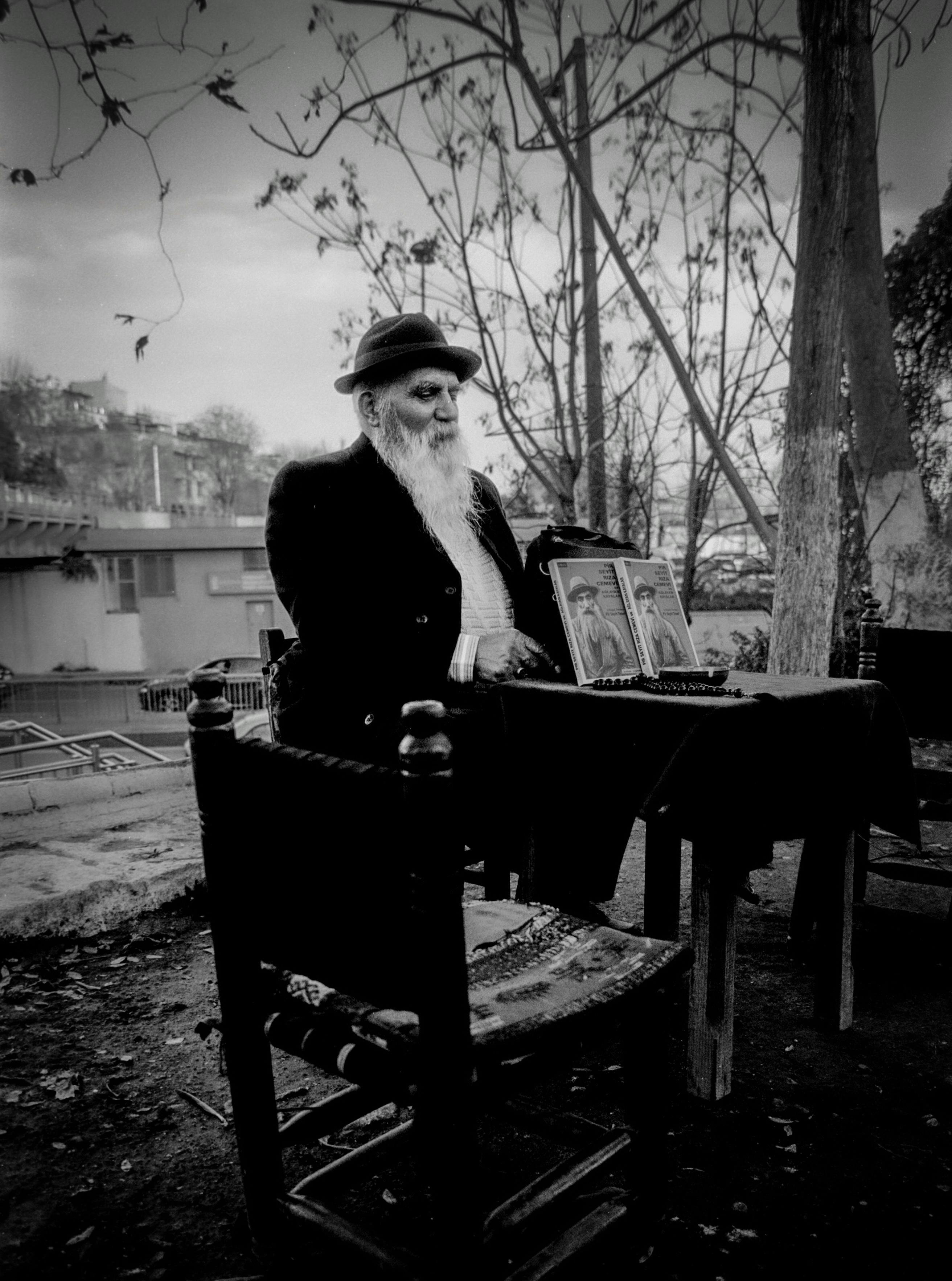 elderly man seated outdoors with vintage photos