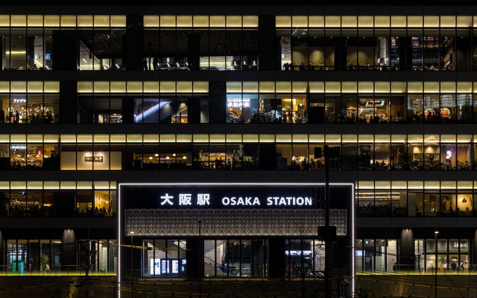 Illuminated facade of Osaka Station at night showcasing modern architecture.