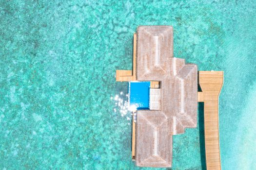 Stunning aerial view of overwater bungalows in turquoise waters, perfect for a tropical getaway.