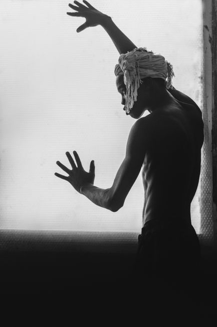 Monochrome silhouette of a stylish man posing with expressive hands indoors.