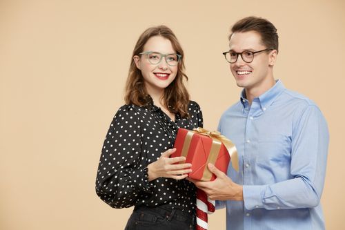 Free Happy couple exchanging gifts with smiles, perfect for holiday themes. Stock Photo