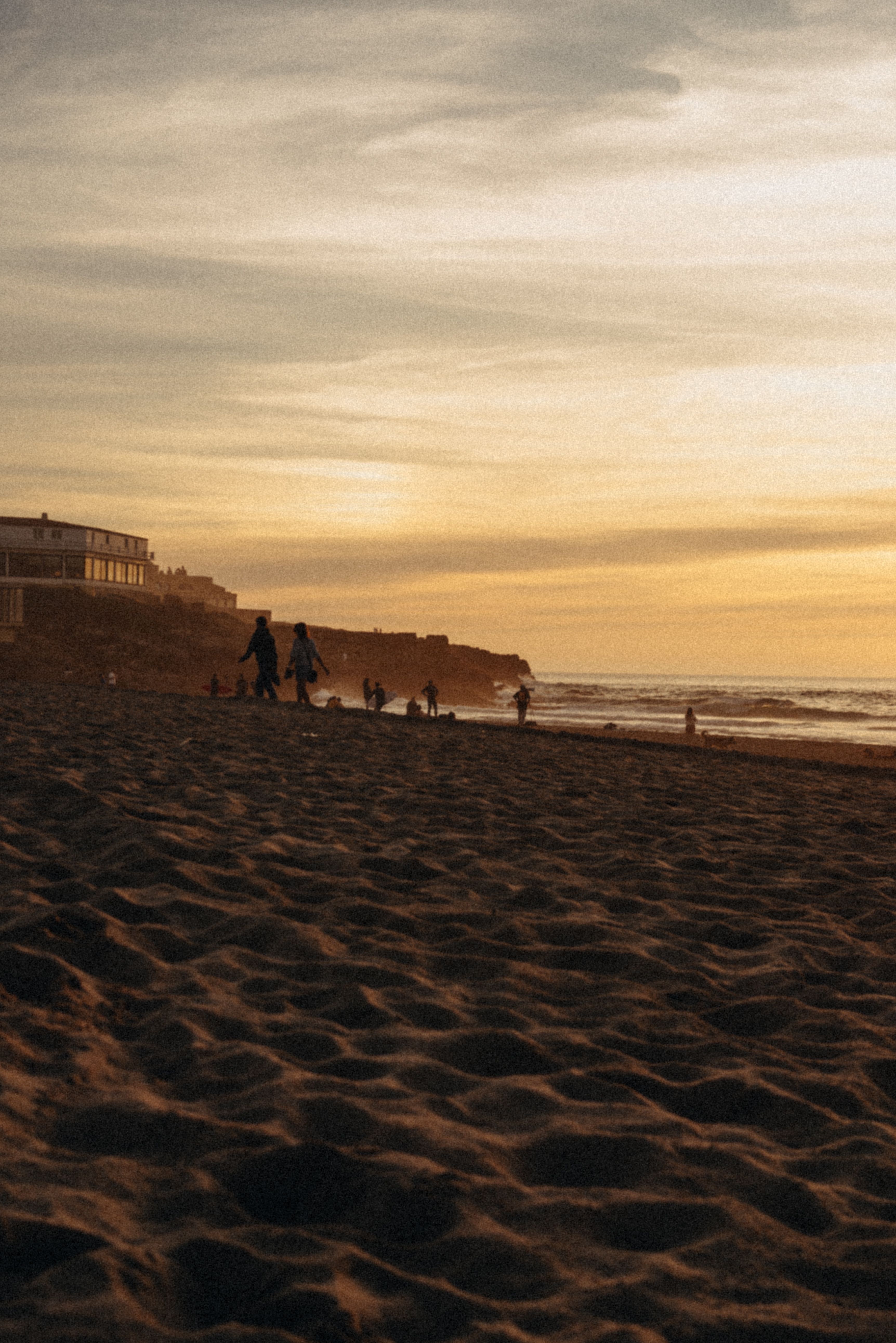 A serene sunset at Maringá Beach with silhouettes of people enjoying the evening by the ocean.