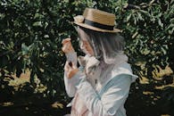 Stylish Woman in Hat Among Green Foliage