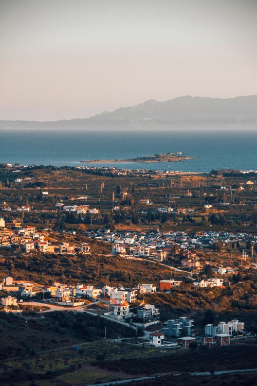 Free Scenic aerial view of a Mediterranean coastal town with mountains in the background during sunset. Stock Photo