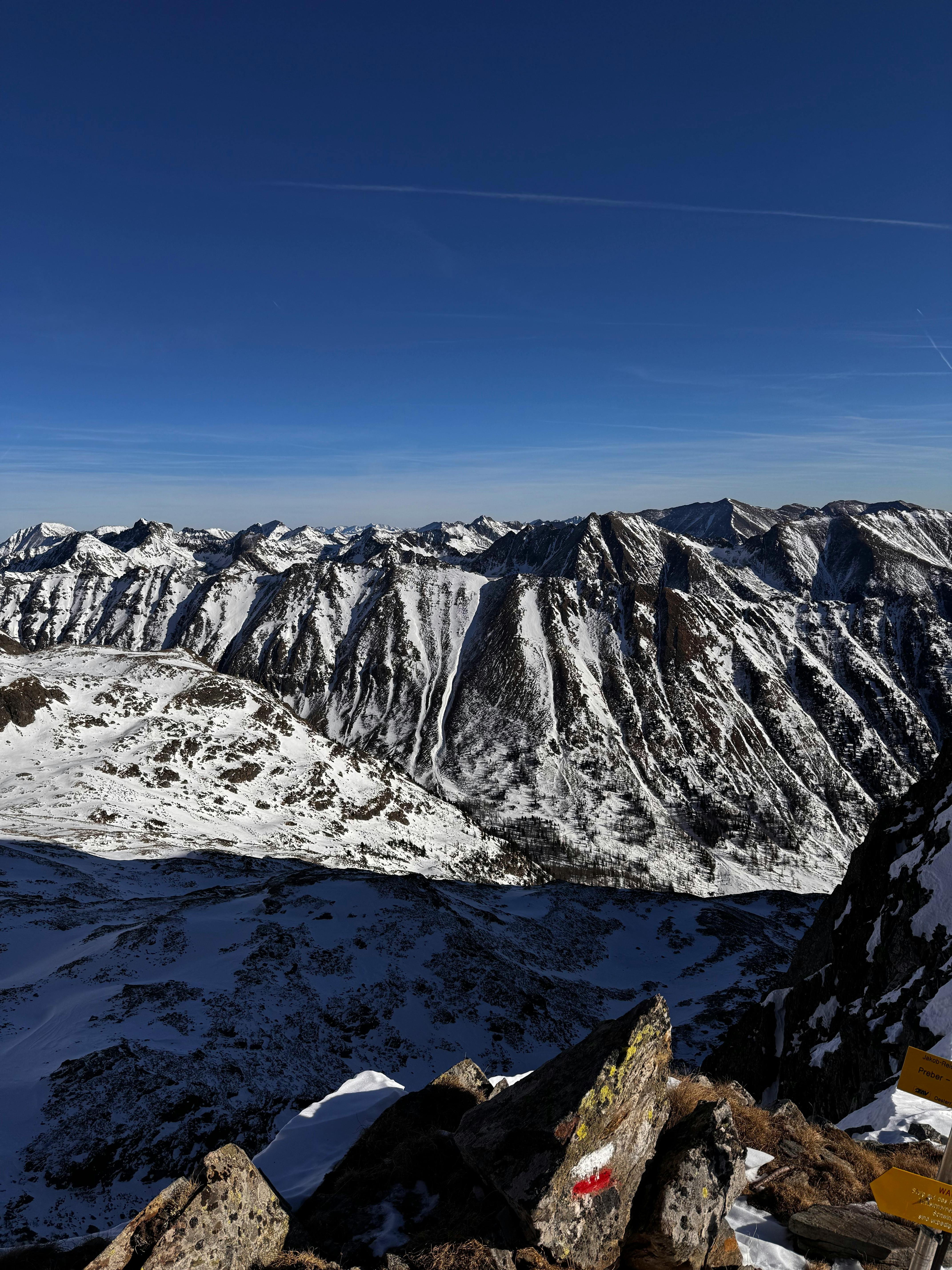Panoramic view of the snow-covered Austrian Alps under a clear blue sky.