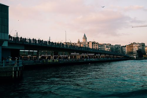 Free Scenic view of Istanbul's Galata Tower and bridge at dusk with silhouettes of people. Stock Photo