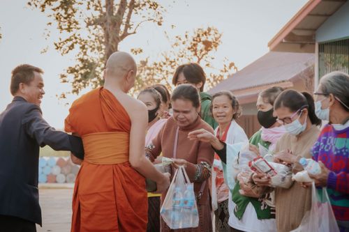 Free A group of locals interacting with a monk, exchanging goods outdoors during the day. Stock Photo