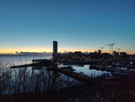 A scenic sunset over Aarhus, Denmark's skyline and harbor, captured with vibrant hues and city lights.