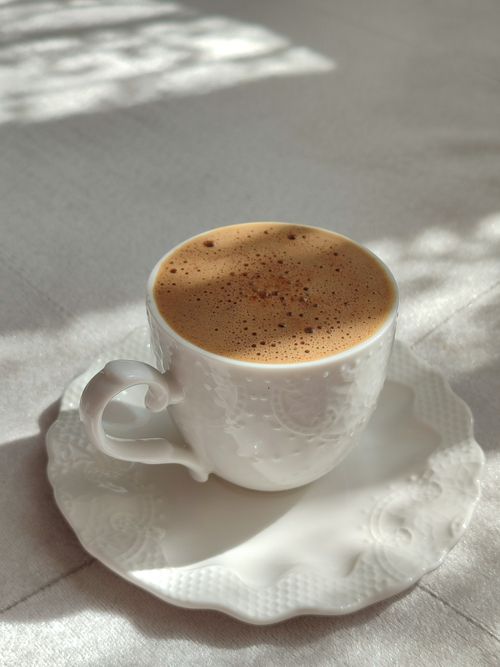 Free Beautifully detailed white porcelain cup filled with frothy coffee, set on a matching saucer. Stock Photo