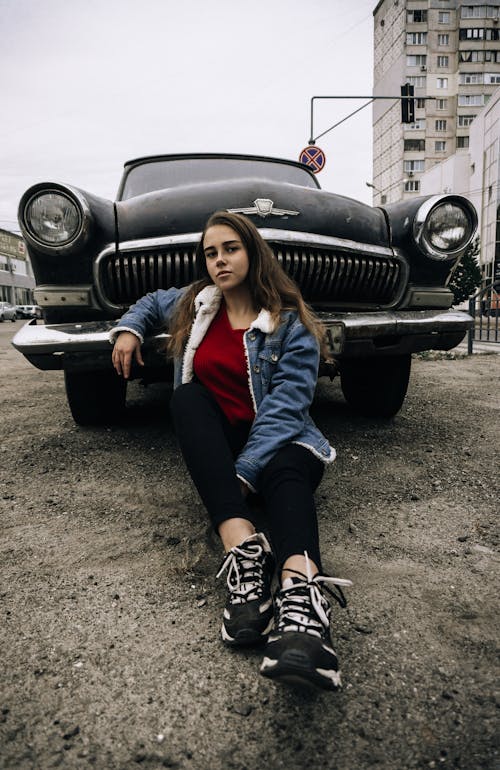 Young woman sitting near retro car