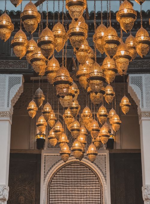 Free Intricate Moroccan lanterns illuminate a historic archway in Fes, Morocco, showcasing rich Islamic architecture. Stock Photo
