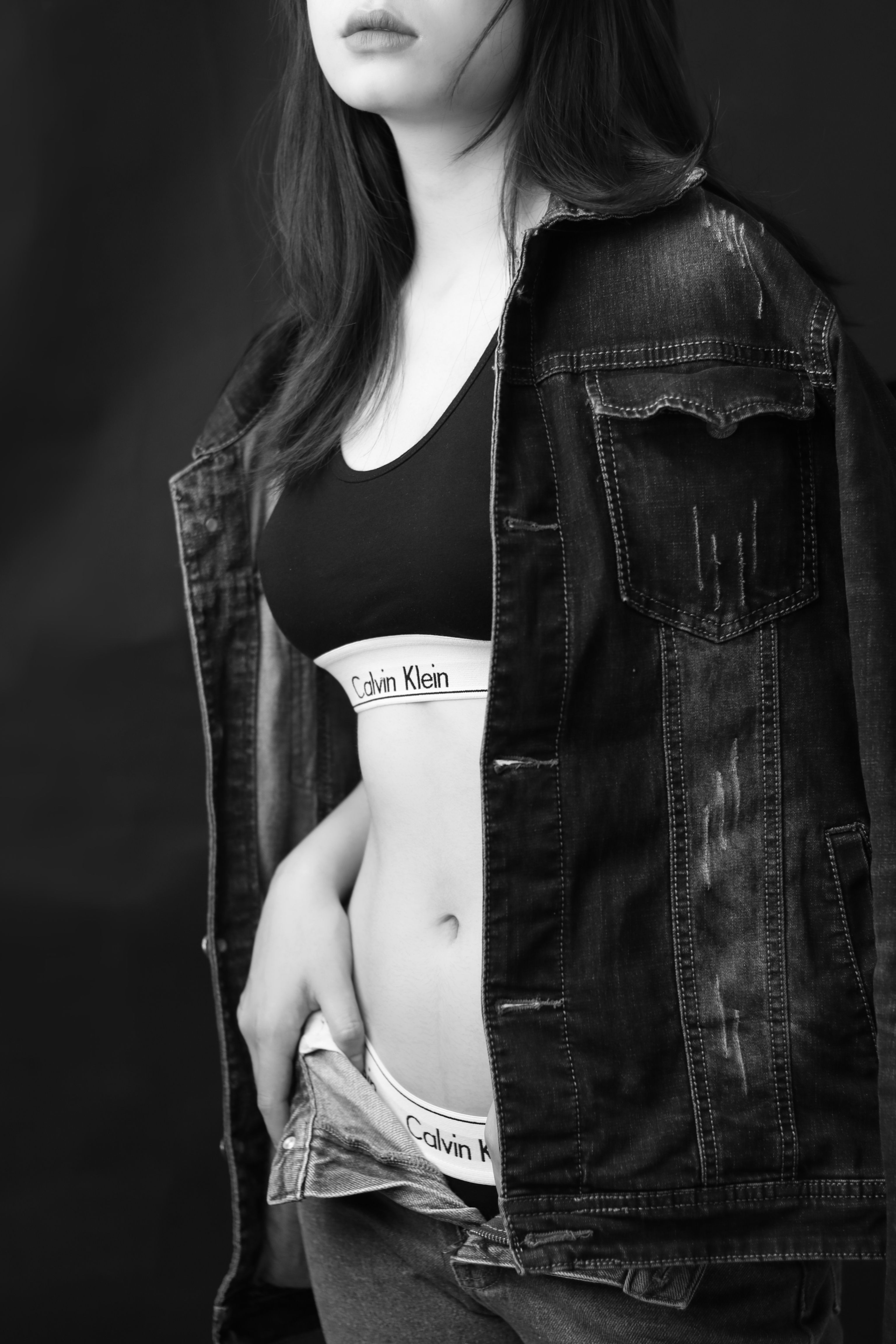Stylish black and white portrait of a woman wearing a denim jacket and branded sportswear.
