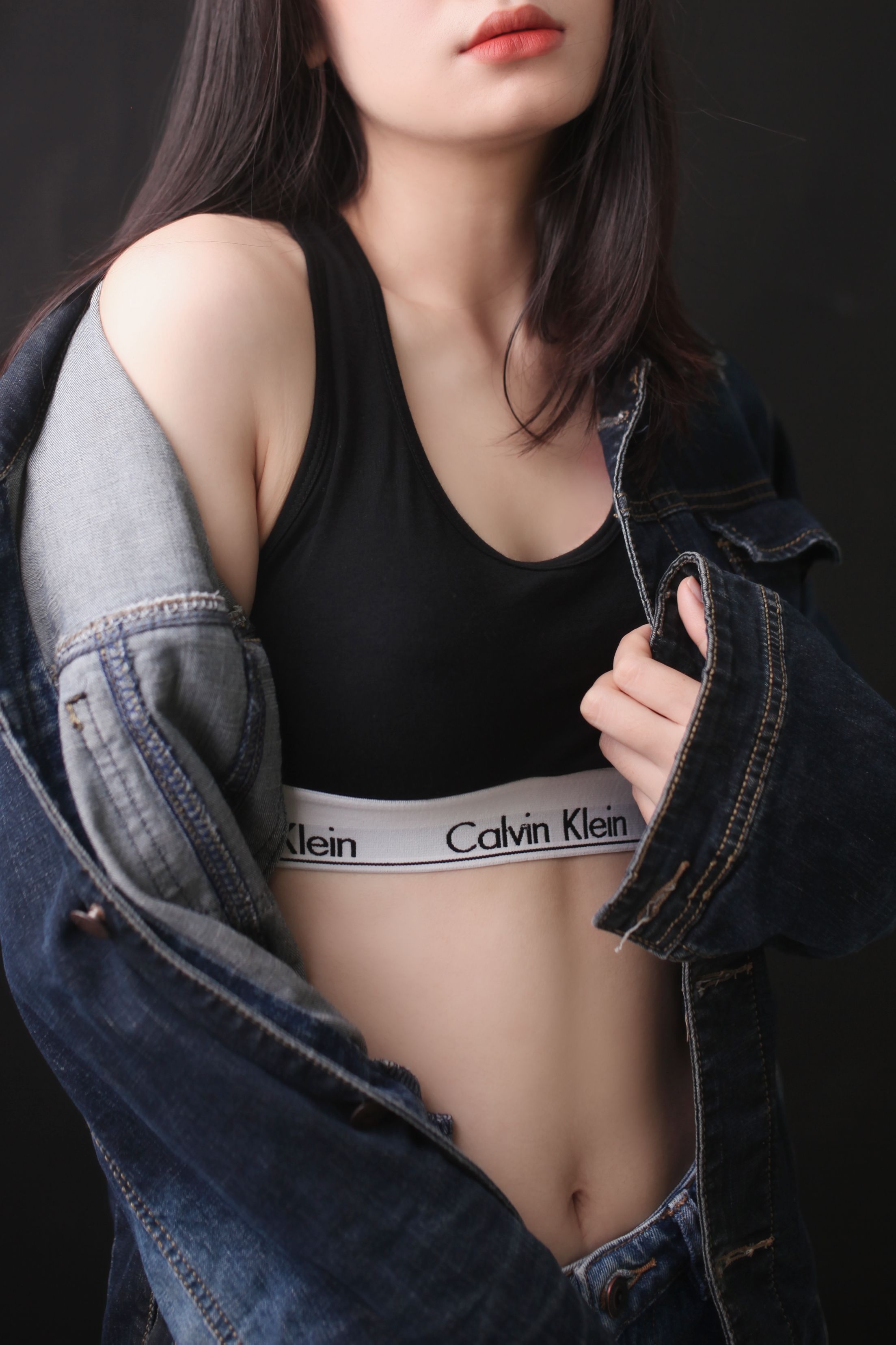 Woman wearing a denim jacket and black sports bra with stylish appeal.
