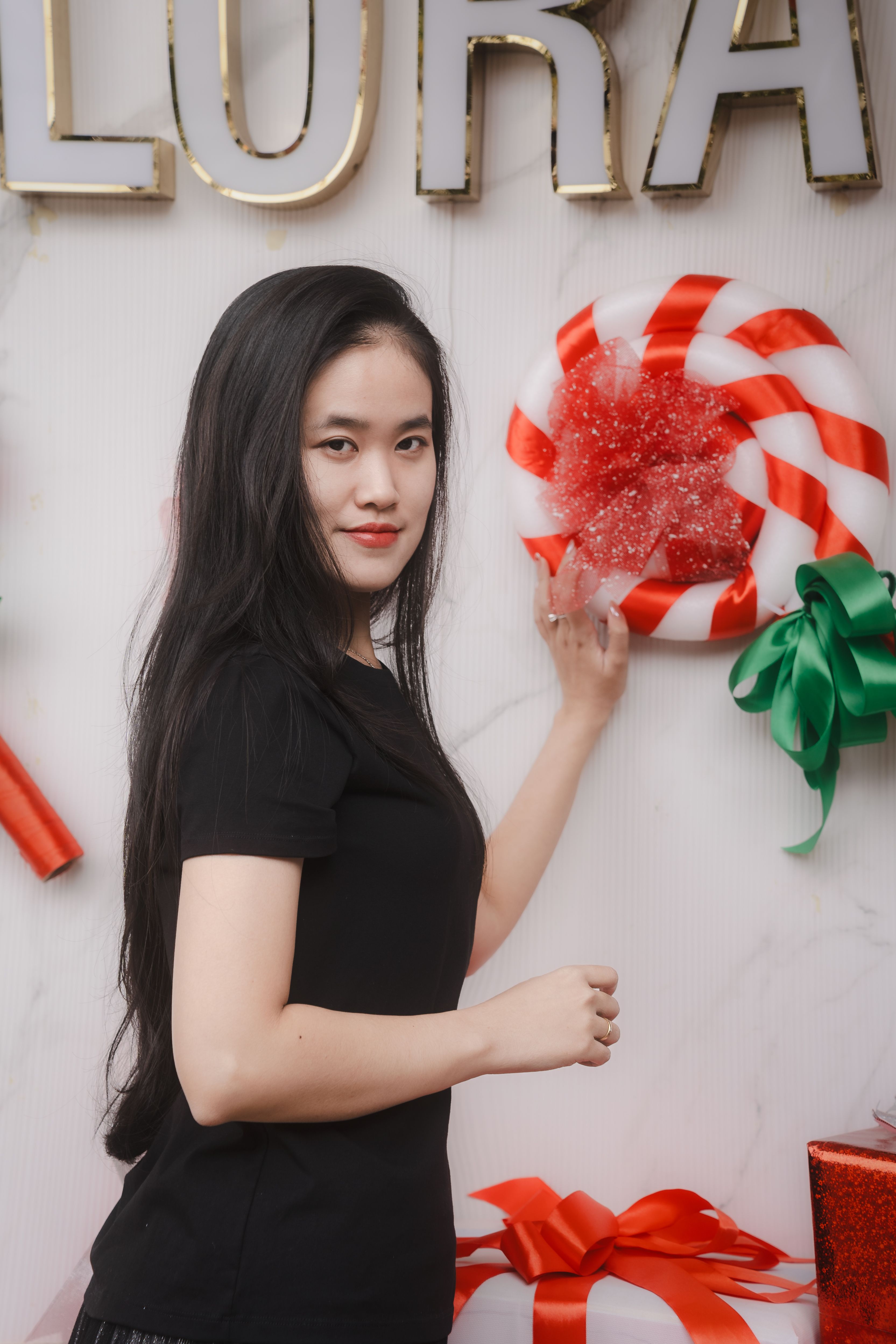 Woman posing with Christmas candy cane decor and gift box.